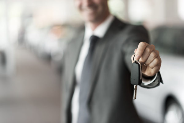 smiling car salesman handing over car keys