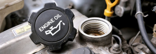 An oil cap resting on top of an oil tank under the hood of a car.